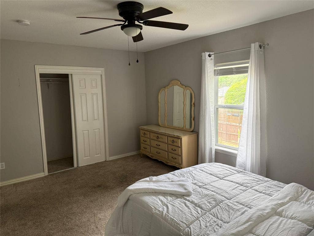 Ceiling fan with integrated lighting, carpeted flooring, window with blinds, and bi-fold closet doors