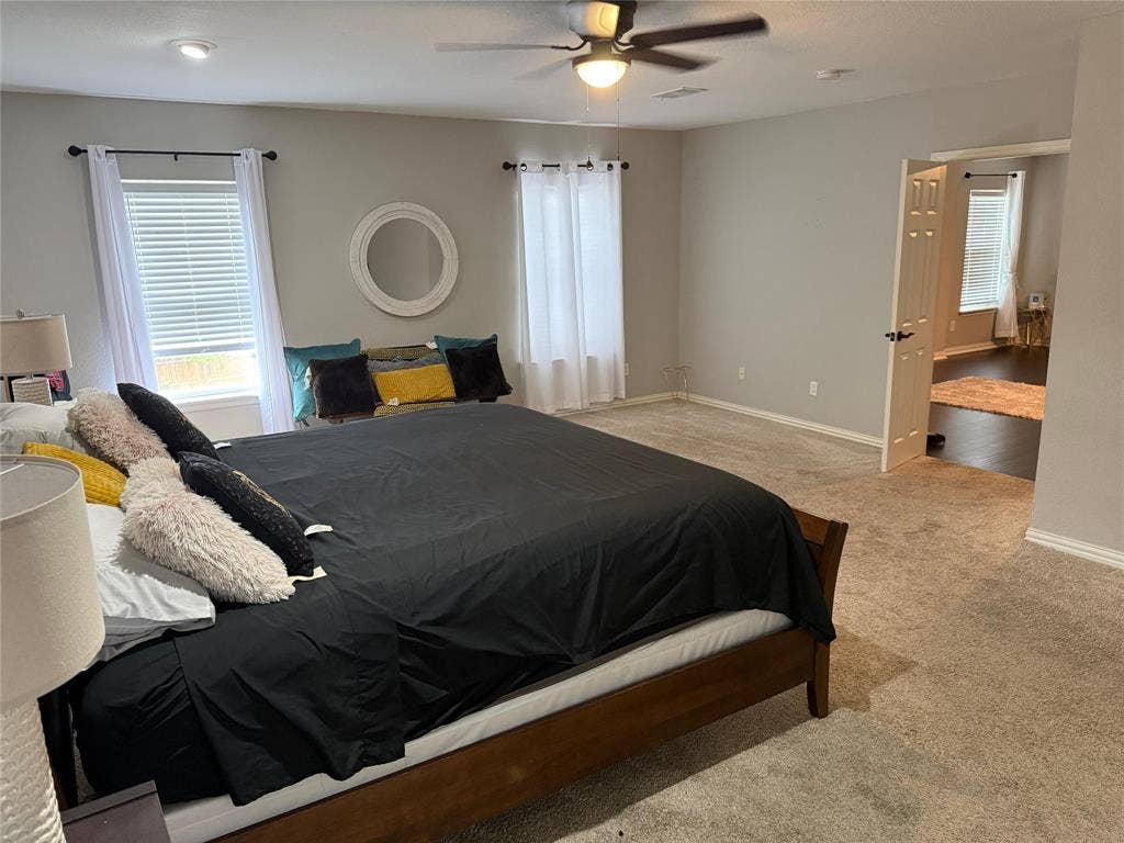 Spacious room with plush carpeting, neutral wall tones, and multiple windows