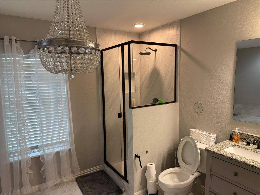 Walk-in shower with dark-framed glass enclosure, tile surround, and rainfall showerhead