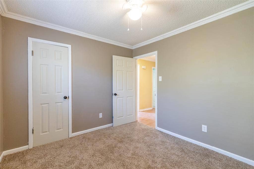 Neutral wall color, crown molding, ceiling fan with light fixture, white trim, and carpeted flooring