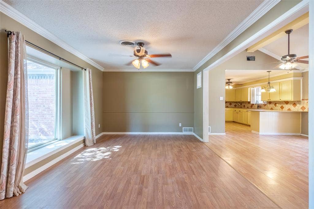 Wood-finish flooring, crown molding, and a ceiling fan in the main living area