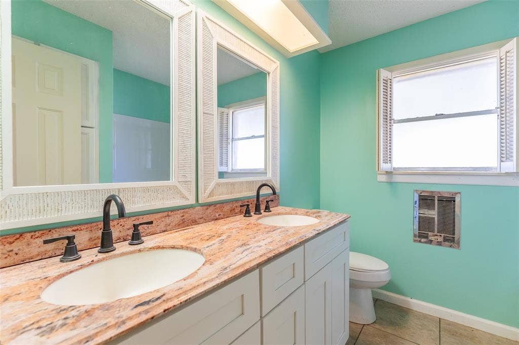 Dual vanity with a stone countertop, twin undermount sinks, and matte black fixtures