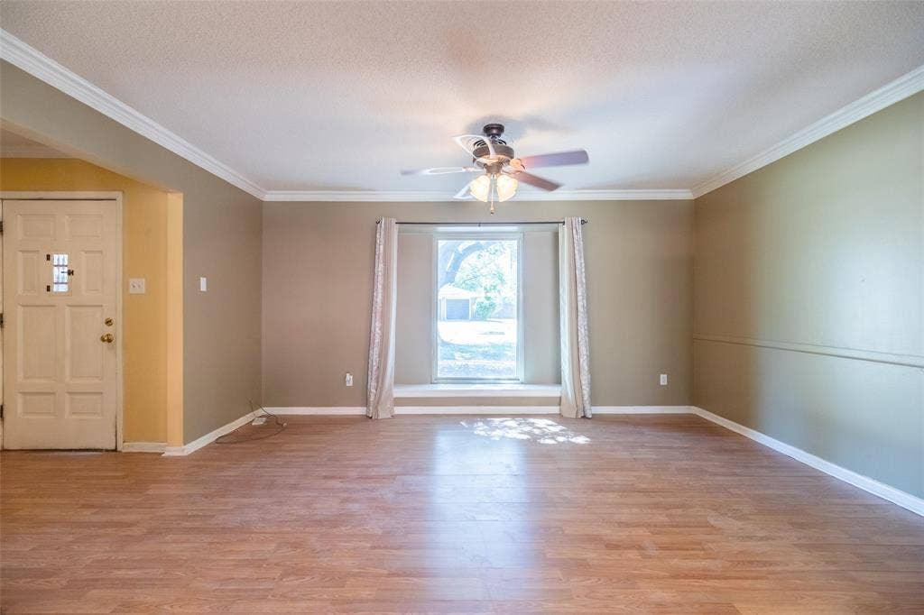 Wood-finish flooring throughout, crown molding, and a ceiling fan with light fixture