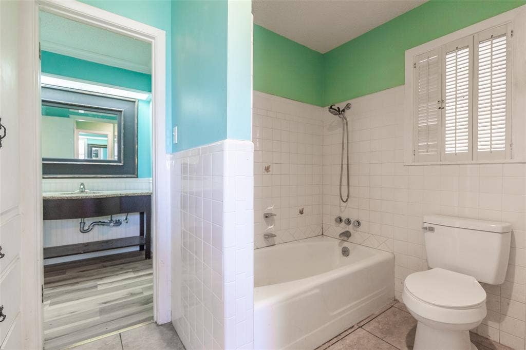 Bathroom featuring a built-in bathtub, white subway tile surround, and a vanity with a surface-mounted sink