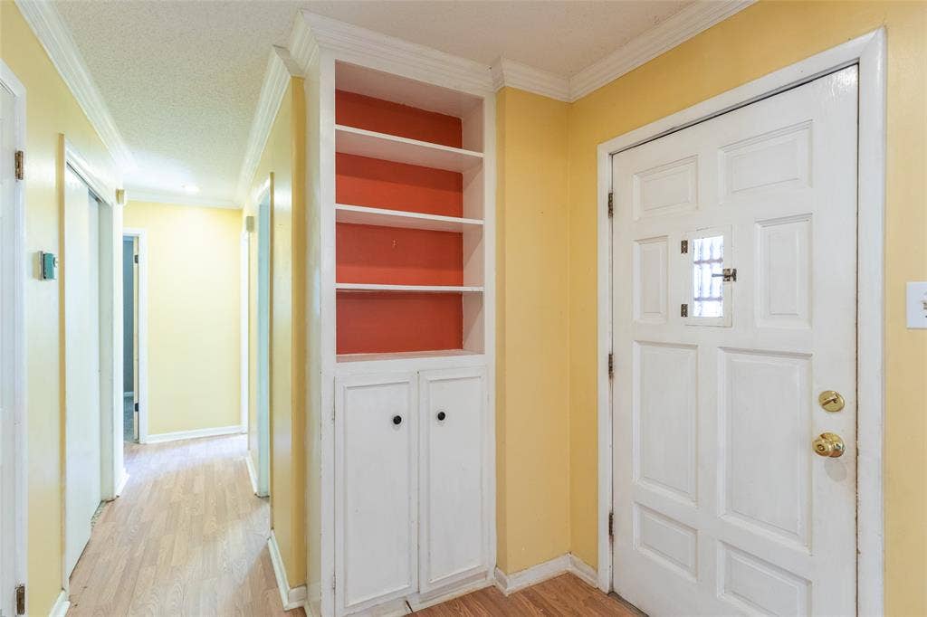 Built-in shelving with lower cabinetry, wood-finish flooring, and white trim details throughout