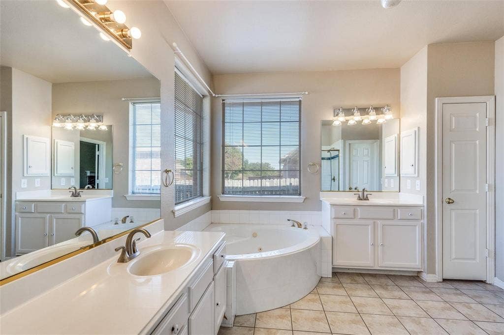 2305 Pittner Lane, Plano, TX 75025 Dual vanity with integrated sinks, a corner soaking tub, two large windows, and tiled flooring