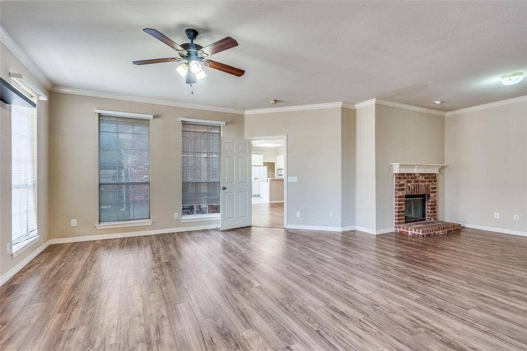 2305 Pittner Lane, Plano, TX 75025 Spacious room featuring wood-finish flooring, a brick fireplace with a white mantel, and multiple windows