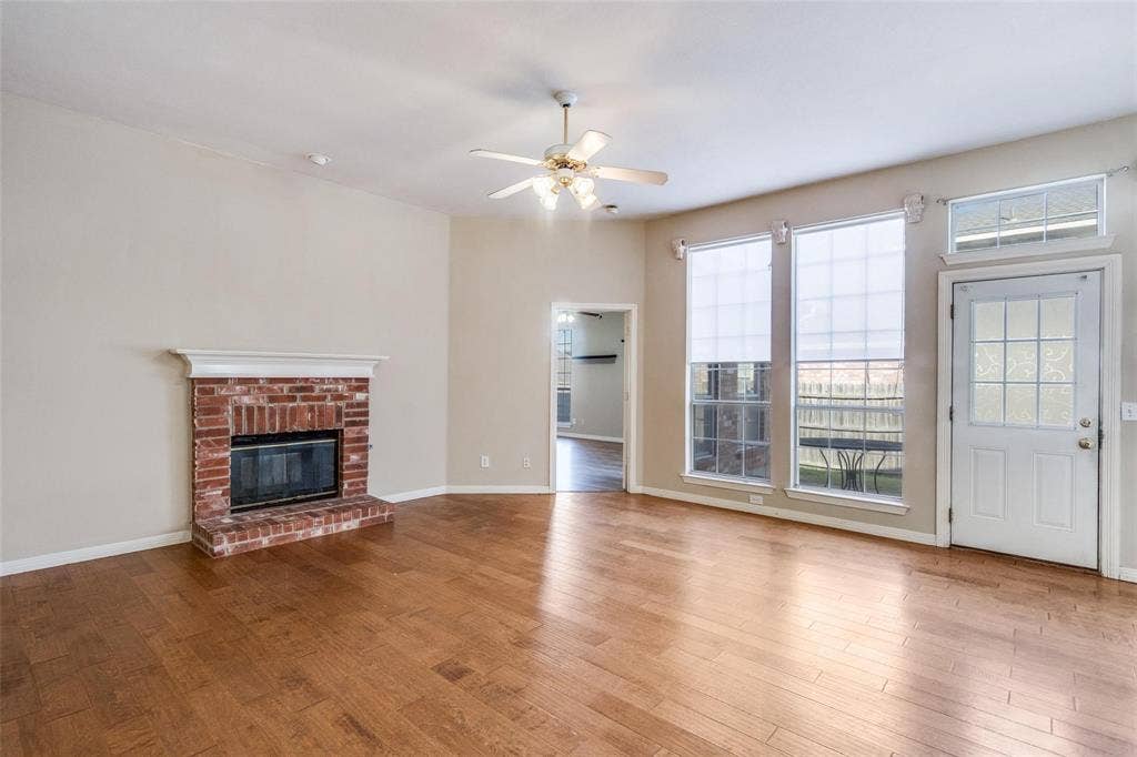 2305 Pittner Lane, Plano, TX 75025 Brick fireplace with a white mantel, wood-finish flooring, and multiple windows