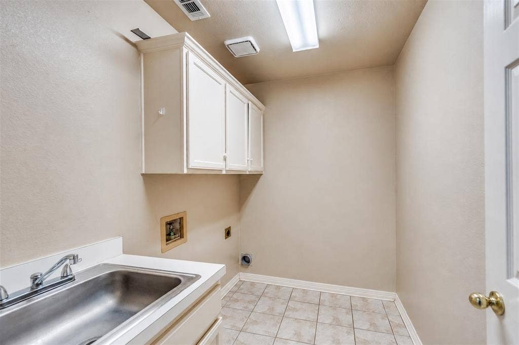 2305 Pittner Lane, Plano, TX 75025 Utility room featuring a stainless steel basin sink, white cabinetry, and tile flooring