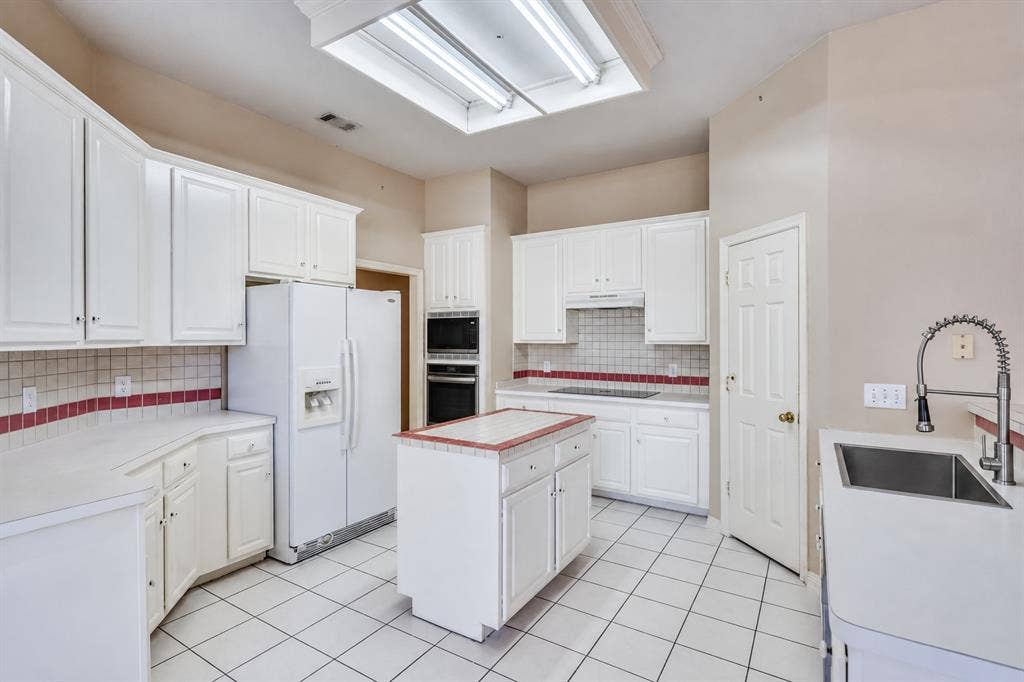 2305 Pittner Lane, Plano, TX 75025 Kitchen featuring white cabinetry, an integrated double oven, an island, a stainless steel sink, and tile flooring