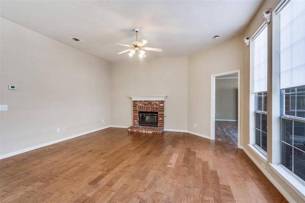 2305 Pittner Lane, Plano, TX 75025 Wood-finish flooring throughout, vaulted ceiling, and a brick fireplace with a white mantel