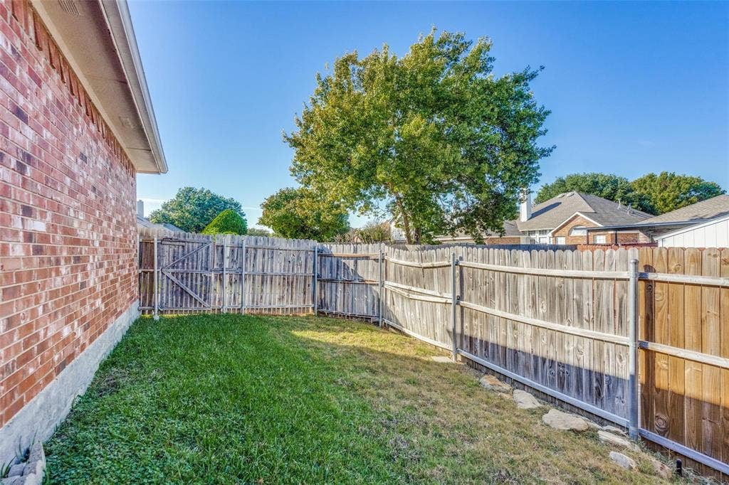 2305 Pittner Lane, Plano, TX 75025 Enclosed backyard featuring a wood fence, a single gate, and a brick exterior