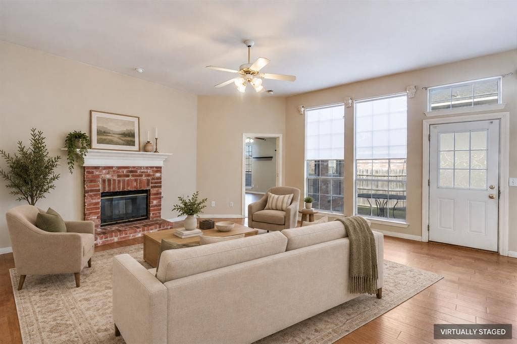 2305 Pittner Lane, Plano, TX 75025 Brick fireplace with a white mantel, wood-finish flooring, ceiling fan, and multiple windows for natural light