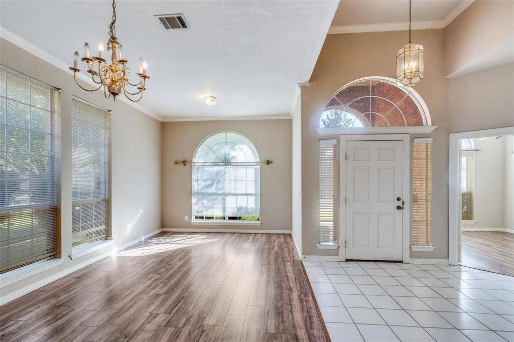 2305 Pittner Lane, Plano, TX 75025 Vaulted entry with transom window and sidelights, wood-finish flooring, white tile flooring, and decorative chandeliers