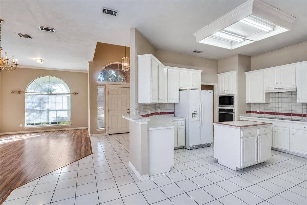 2305 Pittner Lane, Plano, TX 75025 Kitchen featuring white cabinetry, a central island, and white tile flooring