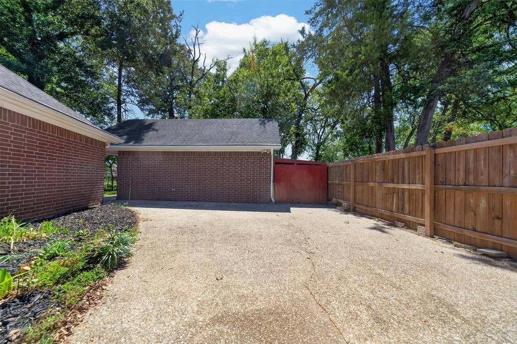 202 Northcreek Drive, Chandler, TX 75758 HOA requires the RV to be behind Fencing. This area was created for that purpose. Notice the Red Wood which s the opening to the area behind the Workshop for additional storage of mowers and etc.