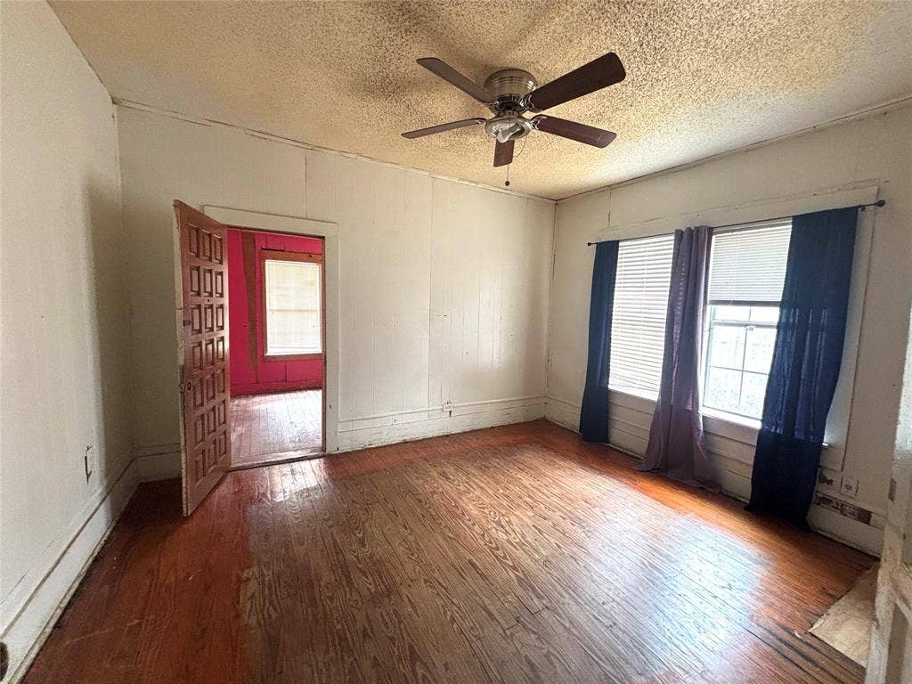 3602 Dunbar Street, Dallas, TX 75215 Wood-finish flooring, wood paneling, ceiling fan with light fixture, and paneled interior door