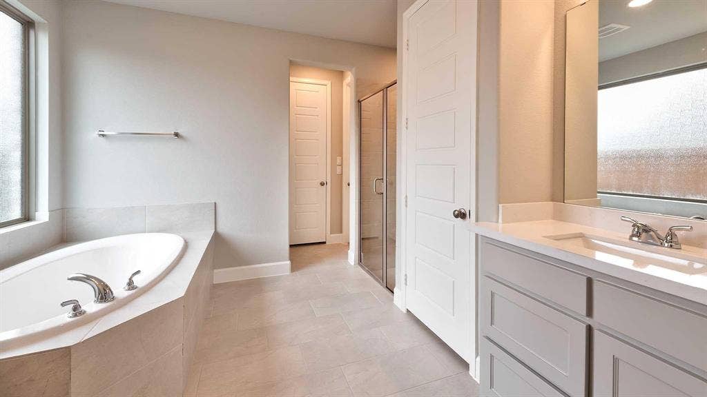 4237 Capstone Road, Midlothian, TX 76065 Soaking tub with a tiled surround, dual-sink vanity with white countertop, and a glass-enclosed shower