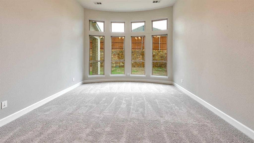 4237 Capstone Road, Midlothian, TX 76065 Curved window wall with multiple panes and transom windows, light gray carpeting, and neutral wall tones