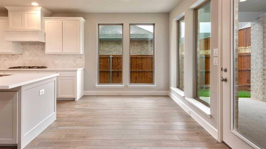 4237 Capstone Road, Midlothian, TX 76065 Open-concept area featuring wood-finish flooring, white cabinetry, a kitchen island with a light-toned countertop, and multiple large windows