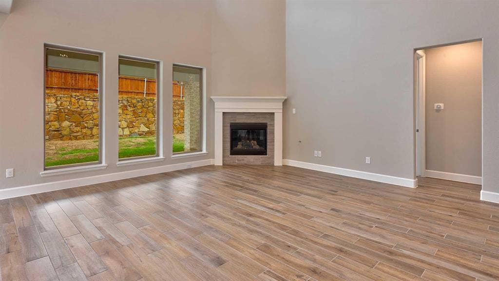 4237 Capstone Road, Midlothian, TX 76065 Vaulted ceilings with abundant natural light, wood-finish flooring, corner gas fireplace with tile surround and mantel, and recessed entry