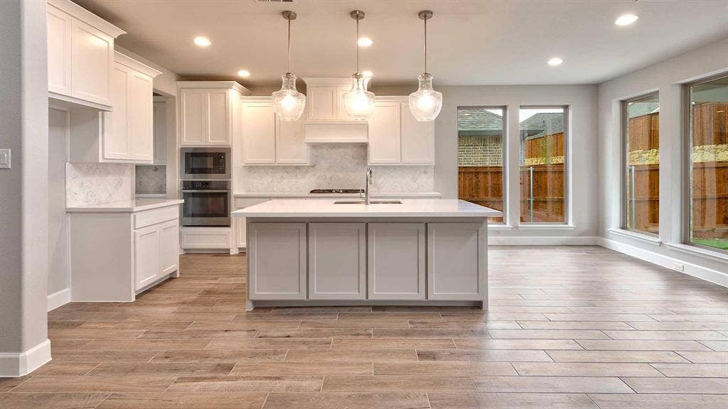 4237 Capstone Road, Midlothian, TX 76065 Open-concept kitchen with white shaker cabinetry, an expansive central island, stainless steel double ovens, and wood-finish flooring