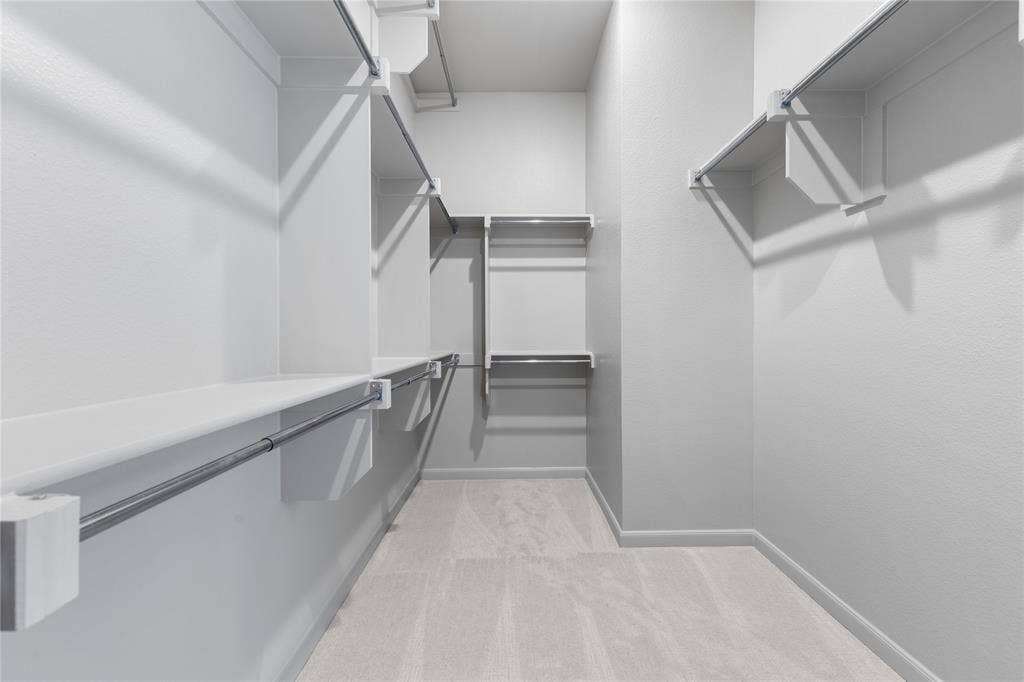 4524 Sunfish Lane, McKinney, TX 75071 Walk-in closet featuring white wall finishes, built-in shelving, chrome hanging rods, and light-toned carpeting