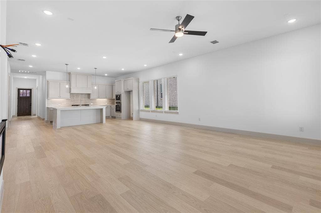 4524 Sunfish Lane, McKinney, TX 75071 Expansive open-concept space featuring light wood-finish flooring, a kitchen island with pendant lighting, recessed ceiling lights, and contemporary ceiling fan