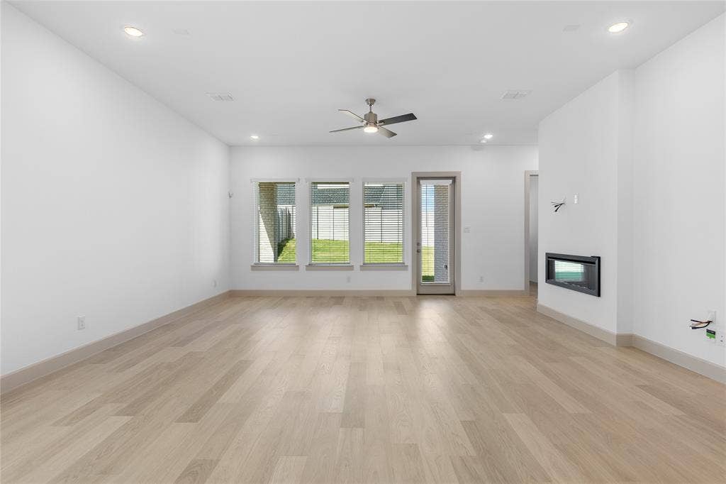 4524 Sunfish Lane, McKinney, TX 75071 Spacious interior with light wood-finish flooring, recessed lighting, and a modern built-in fireplace