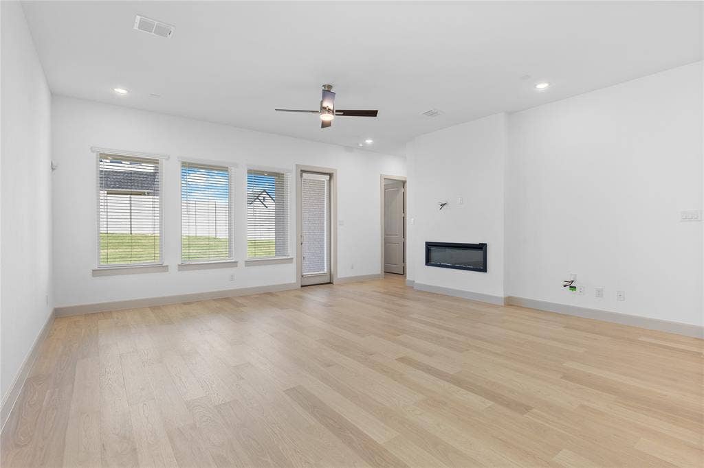 4524 Sunfish Lane, McKinney, TX 75071 Wood-finish flooring, recessed lighting, ceiling fan, multiple windows, and a built-in electric fireplace