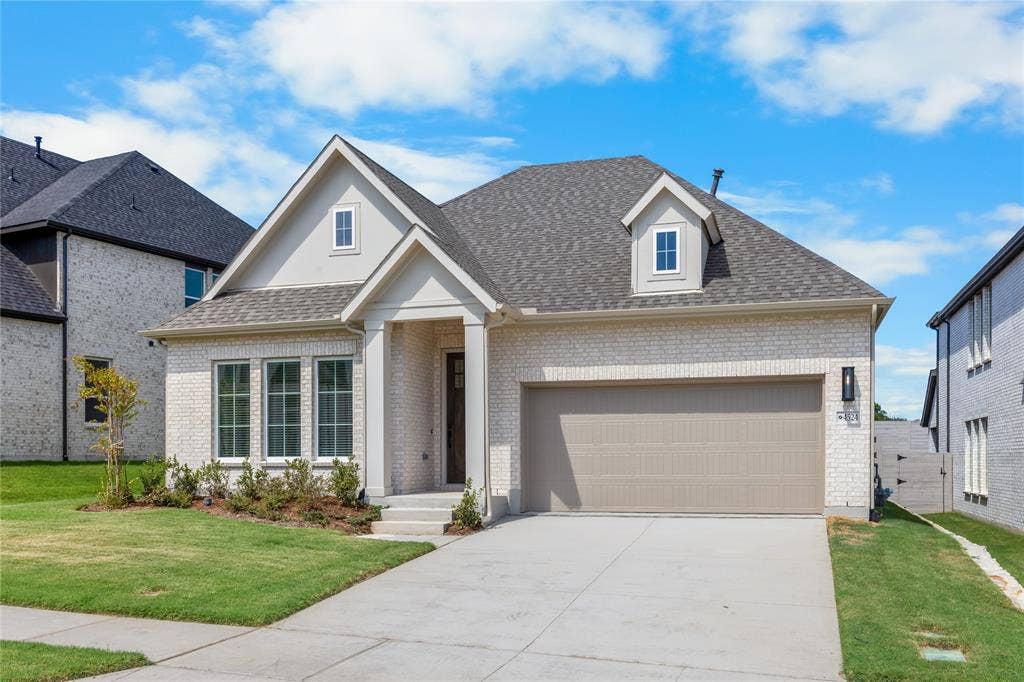 4524 Sunfish Lane, McKinney, TX 75071 White brick exterior with a gray shingle roof, featuring a dormer window and an attached two-car garage