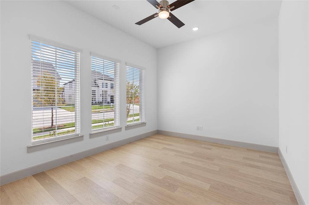 4524 Sunfish Lane, McKinney, TX 75071 Light wood-finish flooring with crisp white walls, contemporary ceiling fan, recessed lighting, and three tall windows