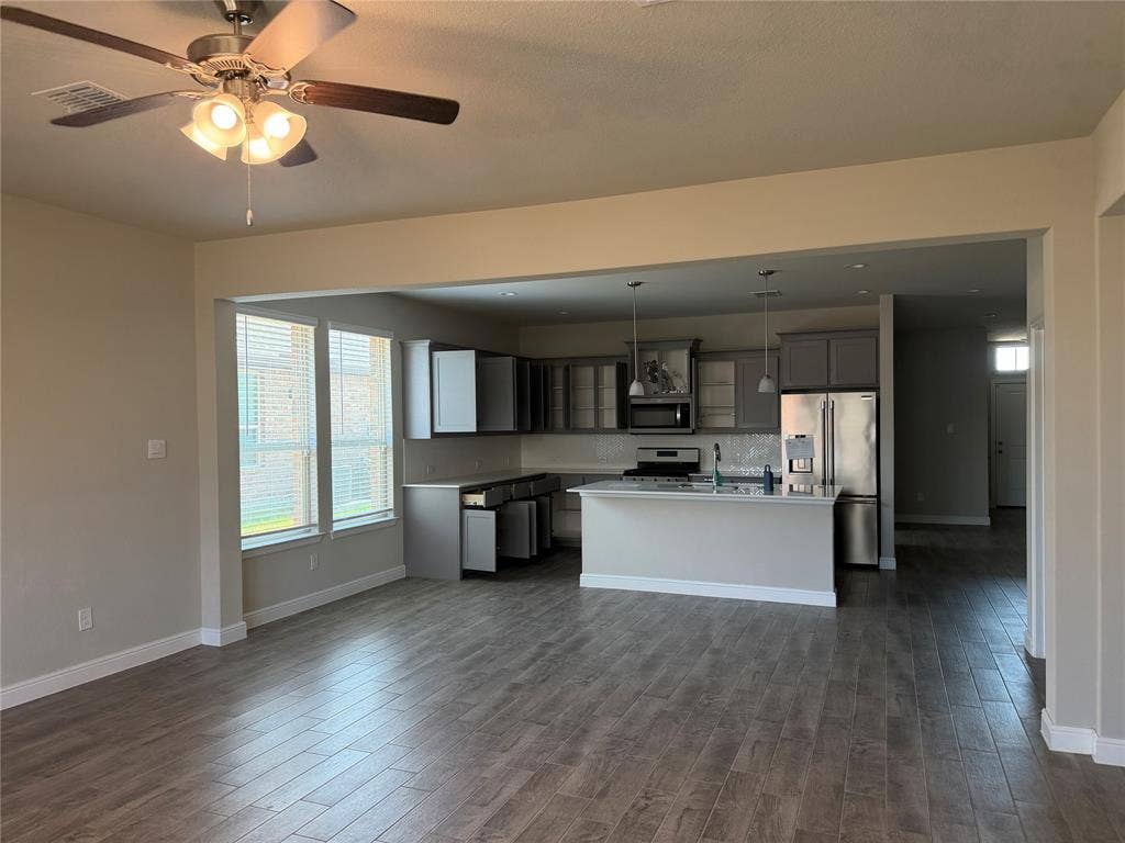 5213 Meadow Lane, Krum, TX 76249 Open-concept living space featuring wood-finish flooring, a ceiling fan, and a kitchen with stainless steel appliances, pendant lighting, and a kitchen island
