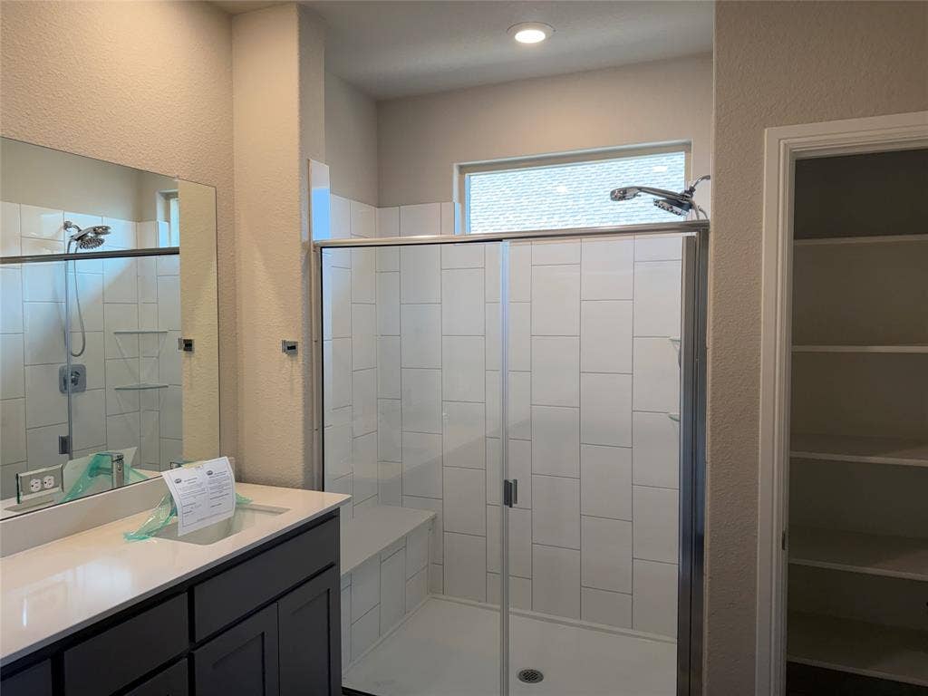 5213 Meadow Lane, Krum, TX 76249 Walk-in shower with white subway tile, built-in shower bench, glass enclosure, and transom window