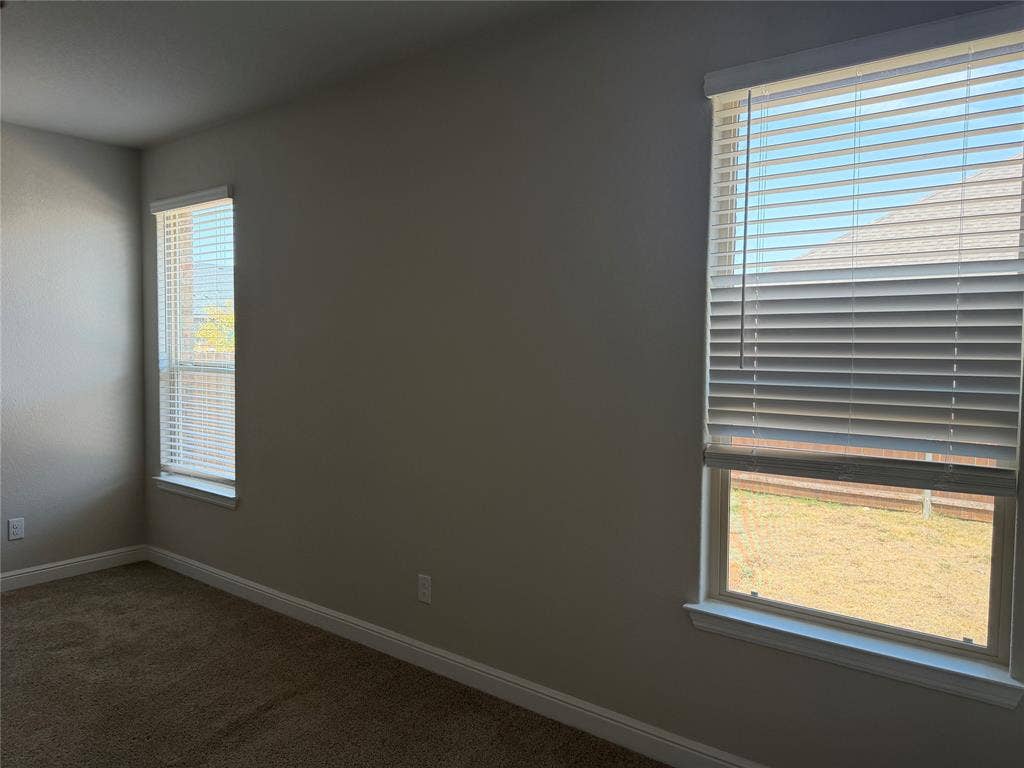 5213 Meadow Lane, Krum, TX 76249 Neutral wall finishes, two windows with blinds, and carpeting
