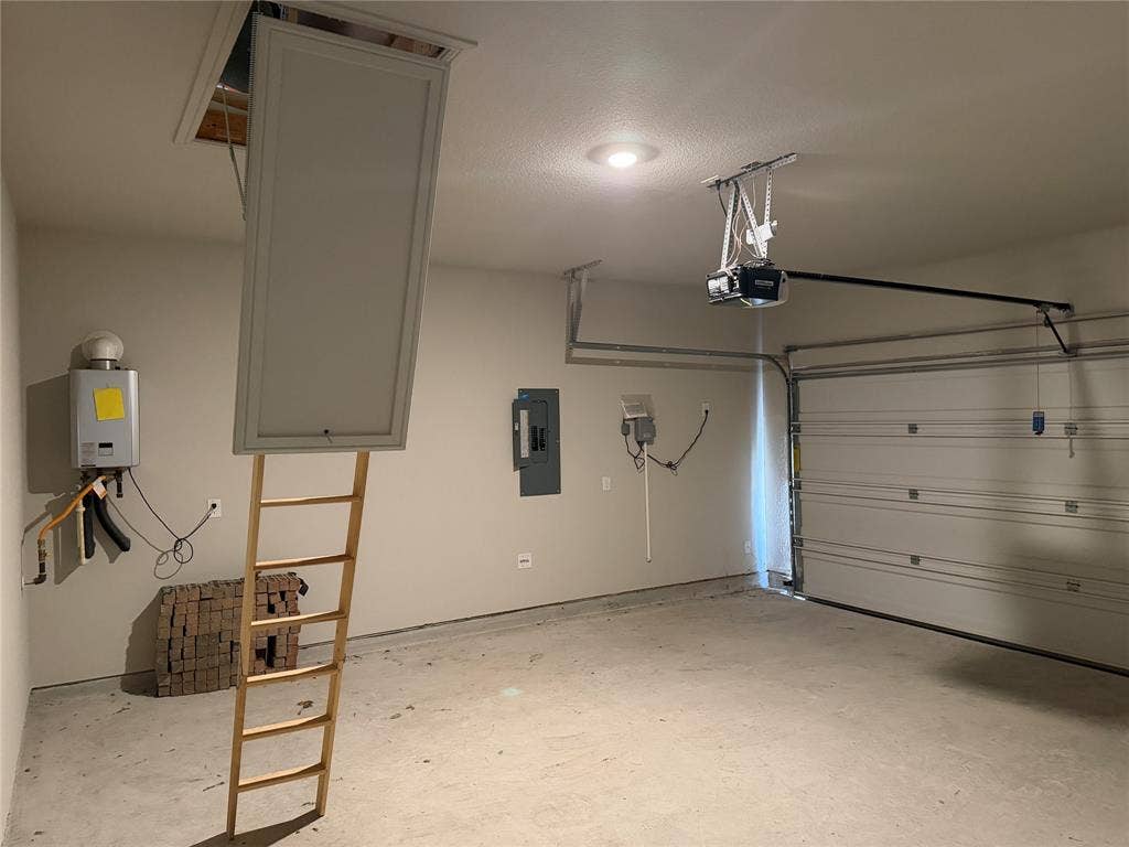5213 Meadow Lane, Krum, TX 76249 Garage with a concrete floor, overhead door, and a wall-mounted water heater