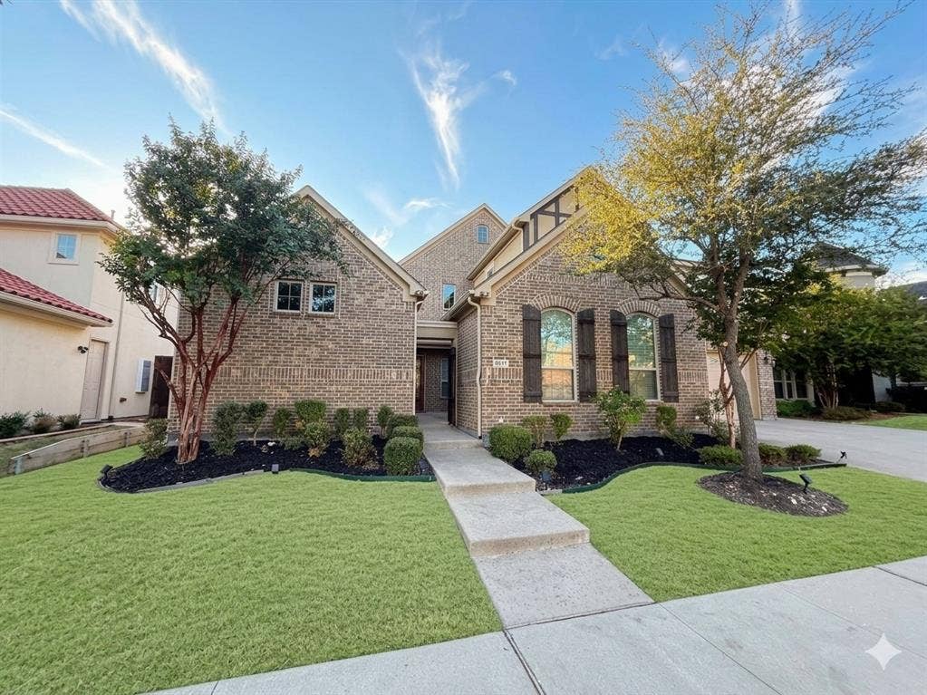 5917 Trantina Lane, Frisco, TX 75035 Brick facade with decorative shutters, symmetrical landscaping, concrete walkway, and established trees