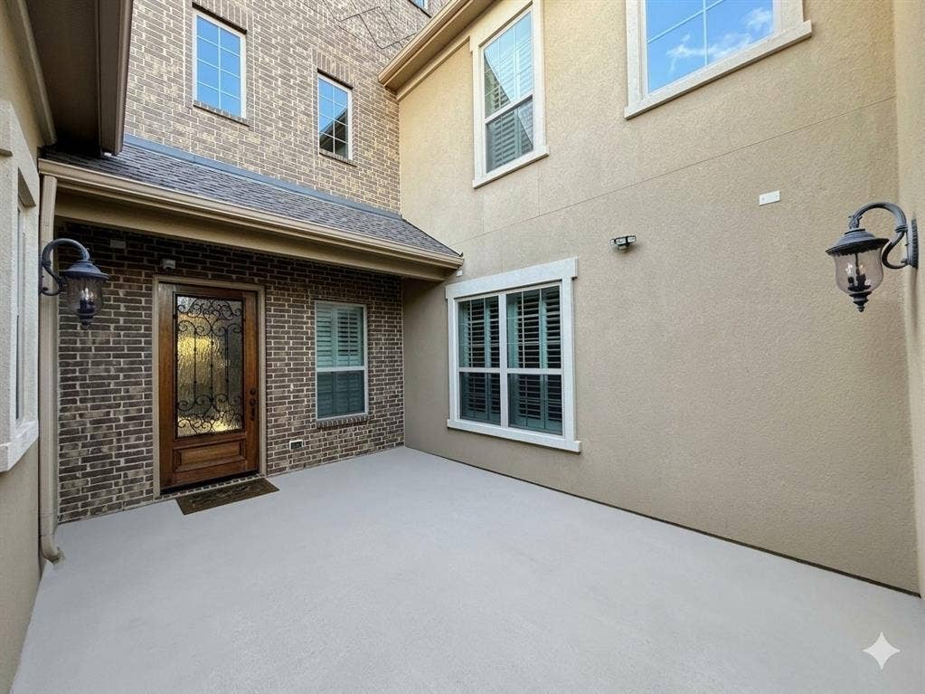 5917 Trantina Lane, Frisco, TX 75035 Entry with a wood door featuring decorative wrought iron and glass, brick and stucco exterior, covered porch, and exterior sconce lighting