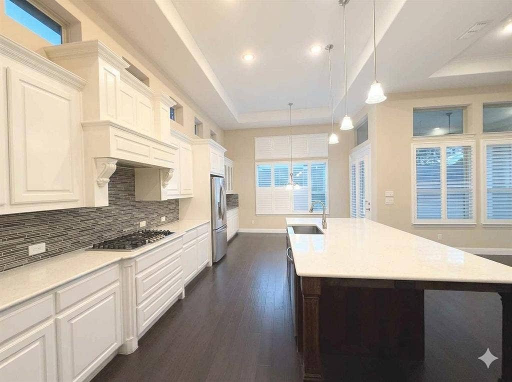 5917 Trantina Lane, Frisco, TX 75035 Spacious kitchen featuring white cabinetry, a large island with an undermount sink, a gas cooktop, stainless steel appliances, and dark wood-finish flooring