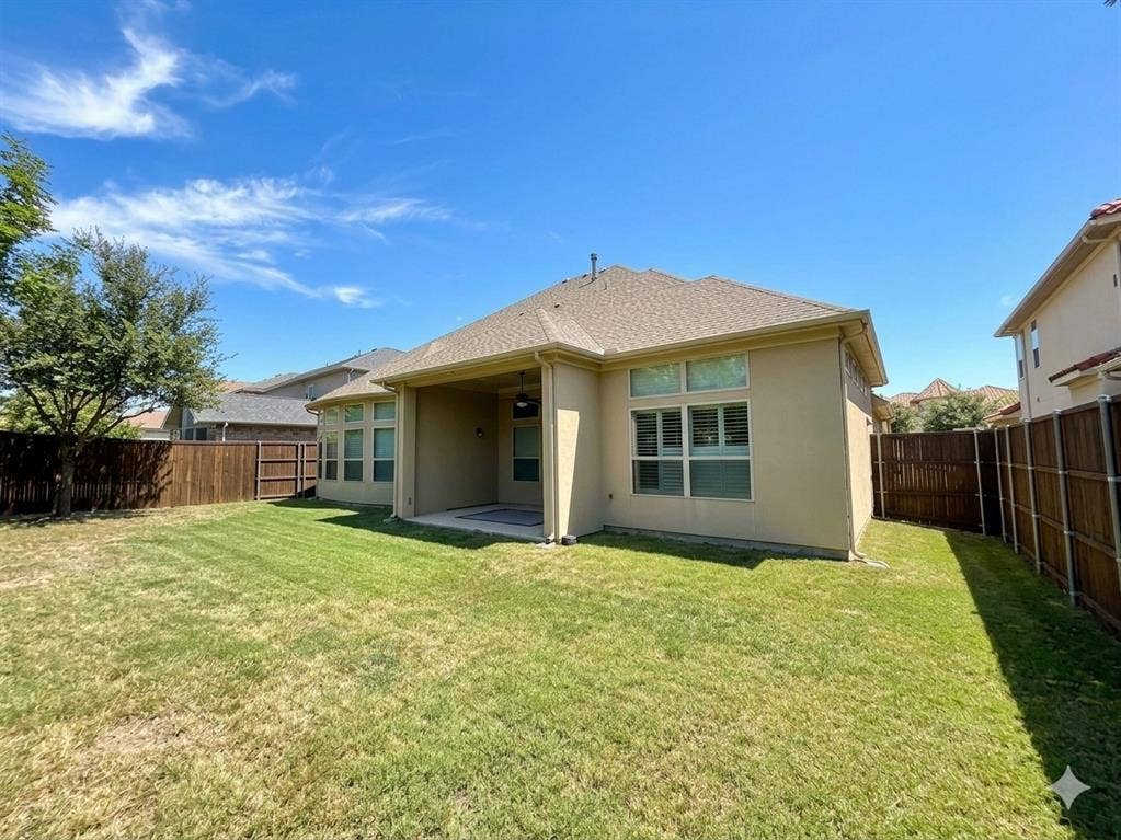 5917 Trantina Lane, Frisco, TX 75035 Expansive grassy yard with wood fencing, a covered patio, and stucco exterior
