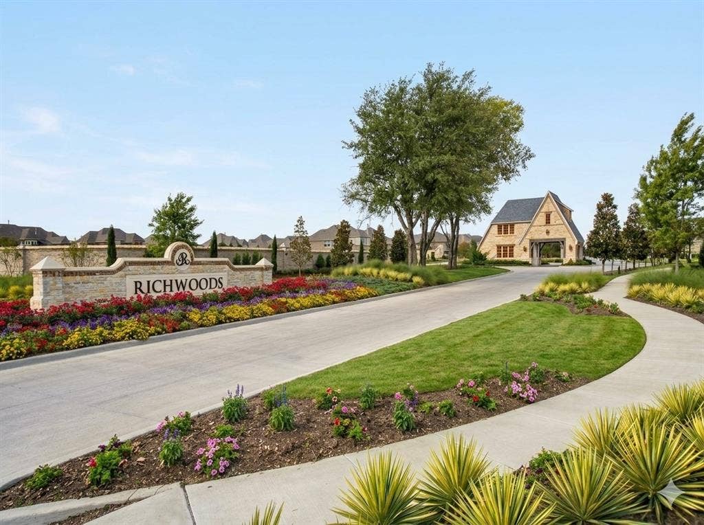 5917 Trantina Lane, Frisco, TX 75035 Entryway featuring a stone-clad monument sign, vibrant perennial landscaping, a curved concrete pathway, and mature trees