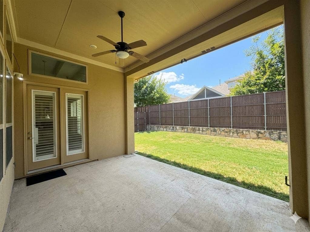 5917 Trantina Lane, Frisco, TX 75035 Covered patio with a ceiling fan, concrete flooring, and direct access to a fenced yard featuring a stone retaining wall