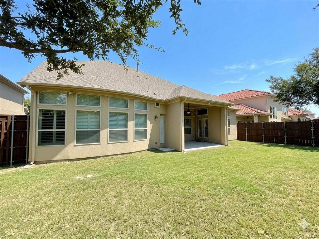 5917 Trantina Lane, Frisco, TX 75035 Expansive backyard featuring a manicured lawn, stucco exterior, and a covered patio with a concrete surface