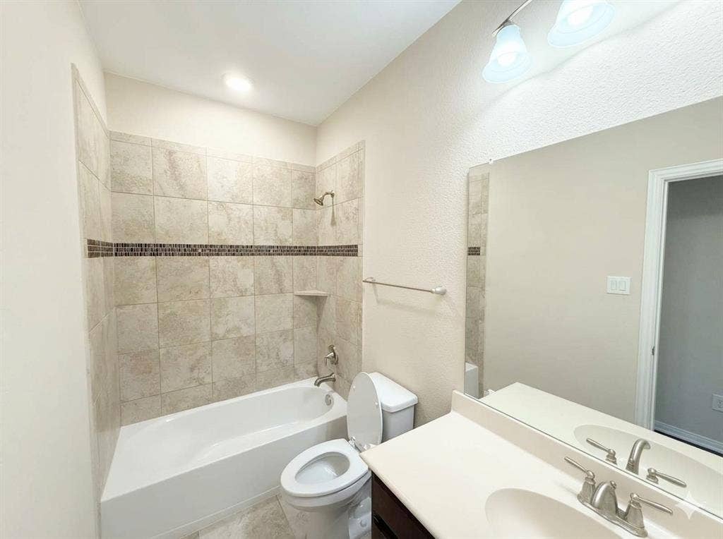 5917 Trantina Lane, Frisco, TX 75035 Bathtub with tiled surround featuring a decorative mosaic accent band and an integrated shelf