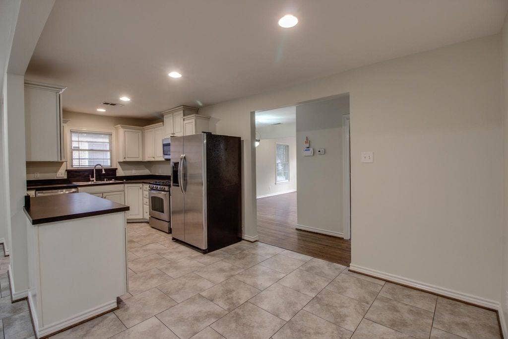 Kitchen featuring white cabinetry, dark countertops, a stainless steel refrigerator, and tiled flooring