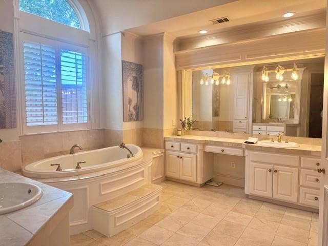 5933 King William Drive, Plano, TX 75093 Spacious bathroom featuring a large soaking tub with steps, a vanity with dual sinks, and a window with white louvered shutters