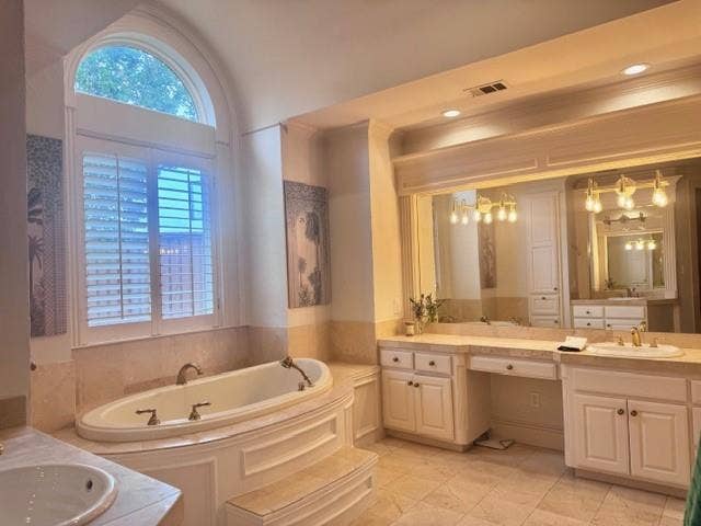 5933 King William Drive, Plano, TX 75093 A spacious bathroom featuring a large soaking tub with integrated steps, an arched window with plantation shutters, dual vanities with integrated sinks, and ample counter space