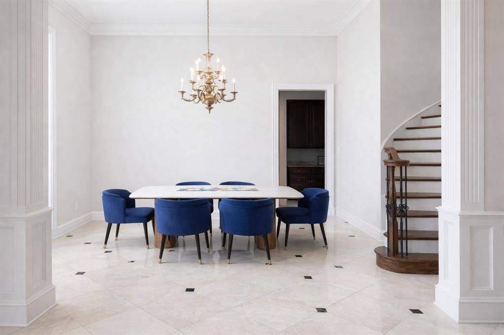 5933 King William Drive, Plano, TX 75093 This room features light-colored tile flooring with dark square inlays, a grand chandelier, and a curved wooden staircase with dark metal railings