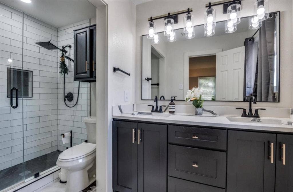 171 Wildwood Drive, DeSoto, TX 75115 Primary bathroom featuring a double-sink vanity, dark cabinetry, and glass-enclosed shower.