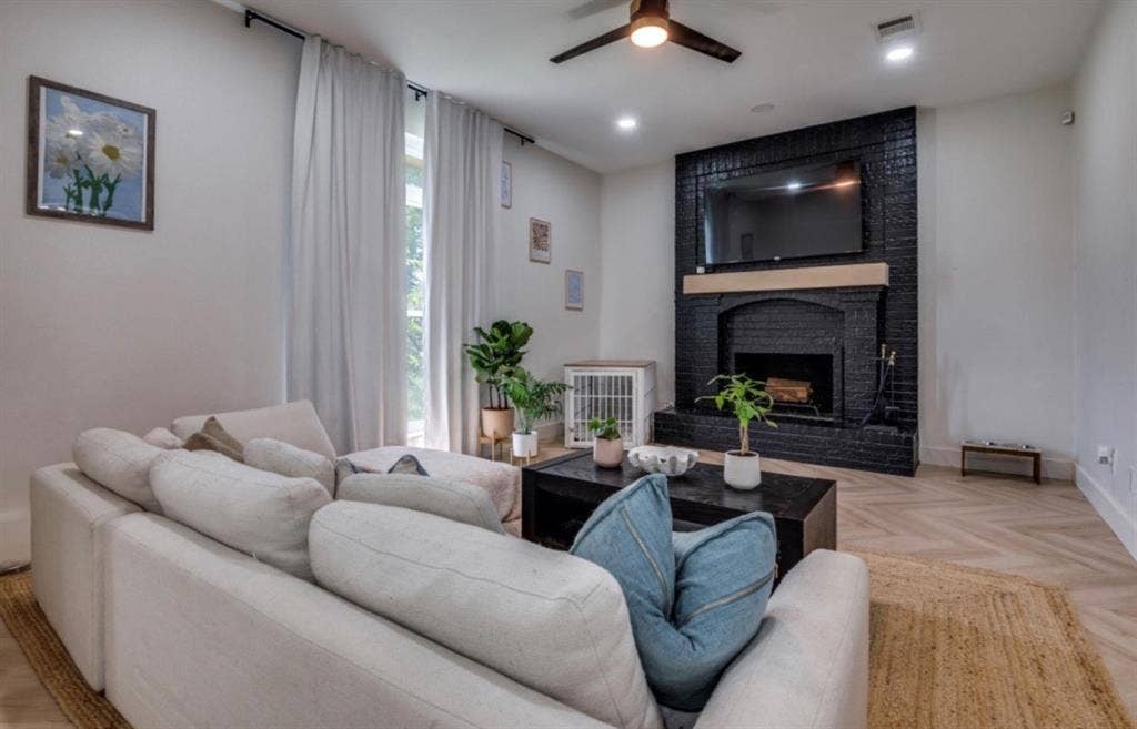 171 Wildwood Drive, DeSoto, TX 75115 Black brick fireplace with wood mantel, herringbone wood-finish flooring, recessed lighting, and ceiling fan